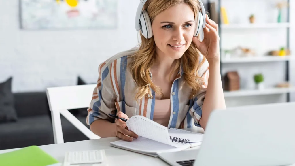 eine Frau sitzt am Schreibtisch mit Kopfhörern